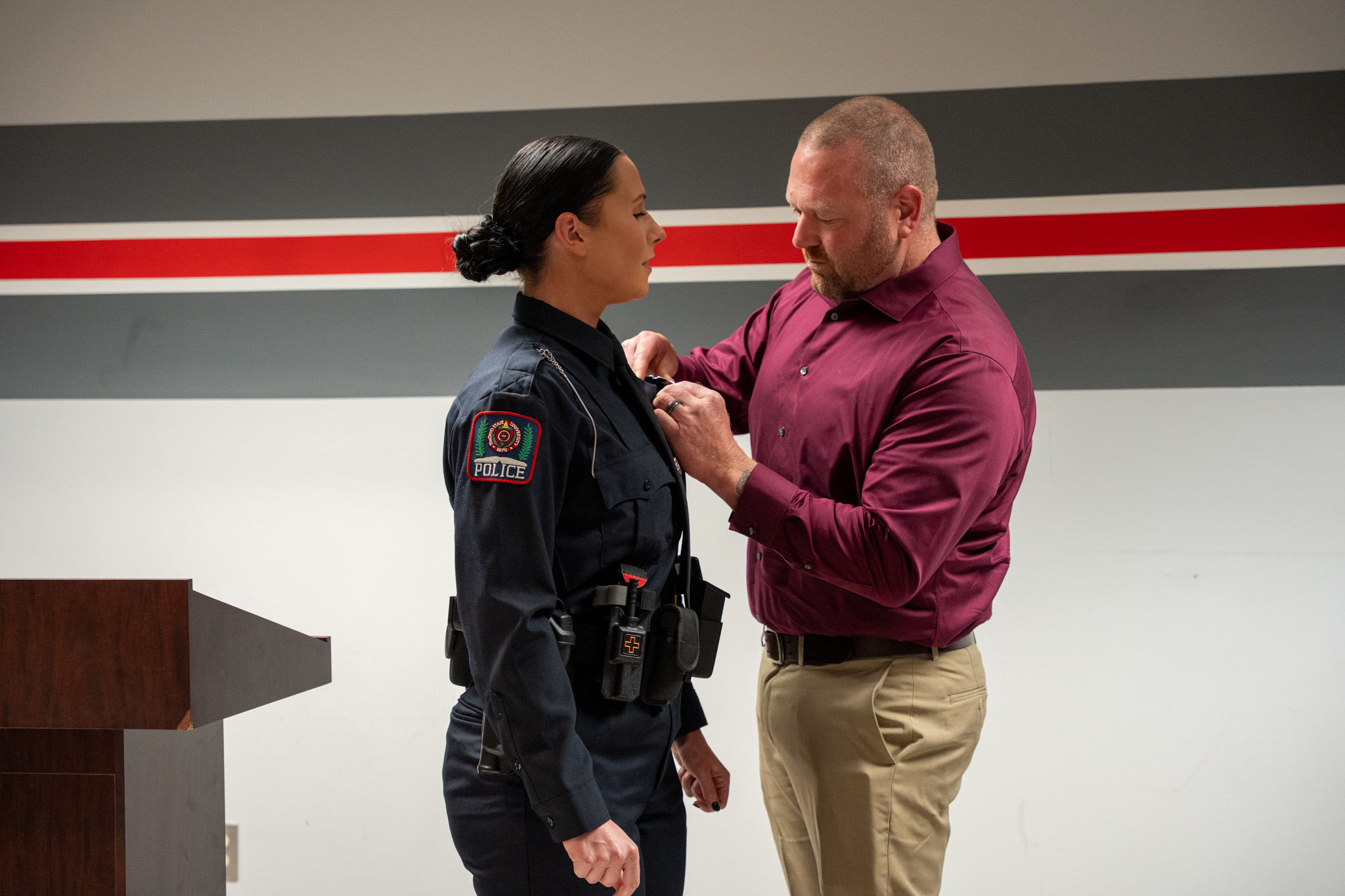 A man pinning the badge on a female officer.