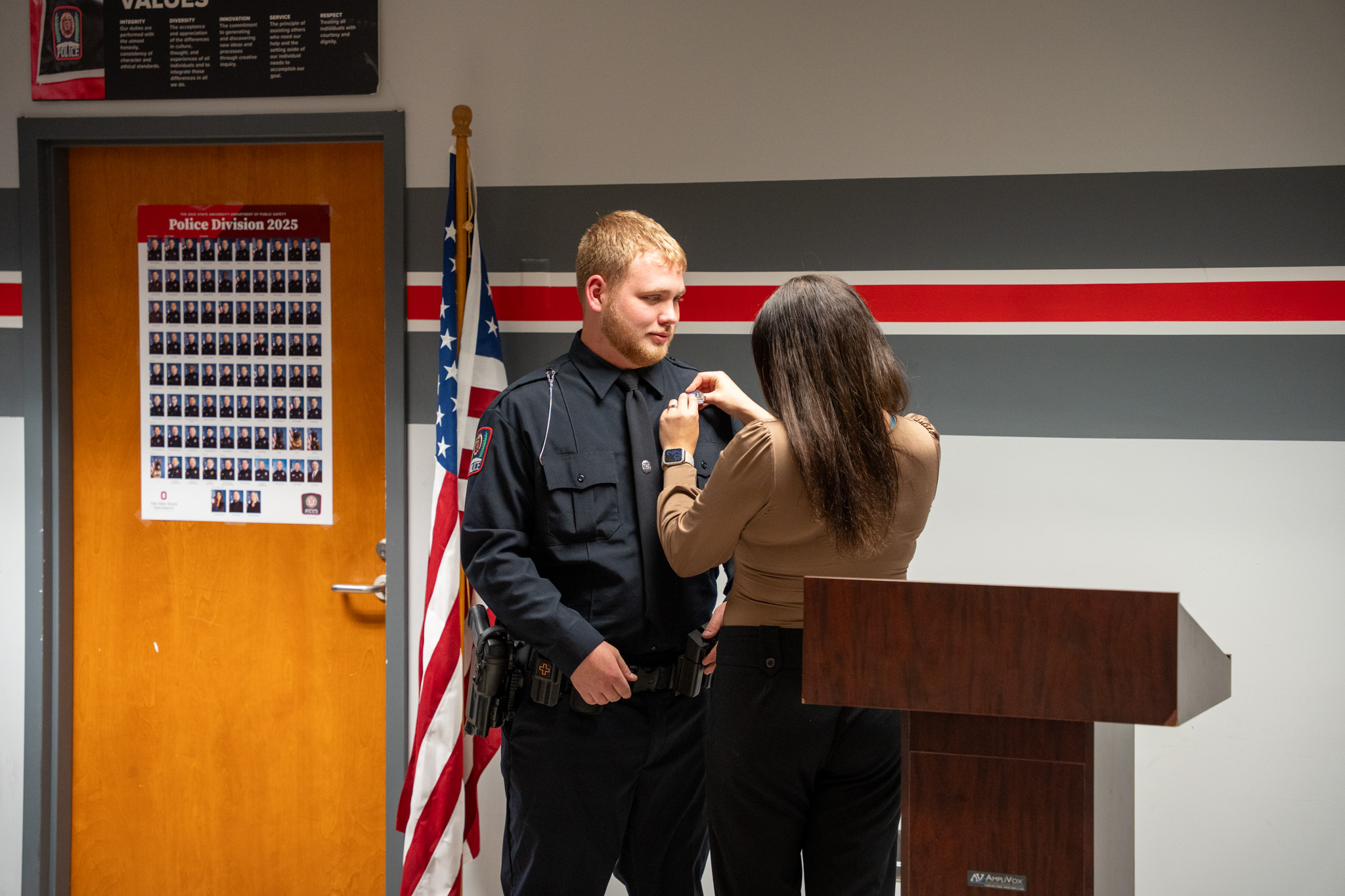 A woman pinning a badge on a male officer.