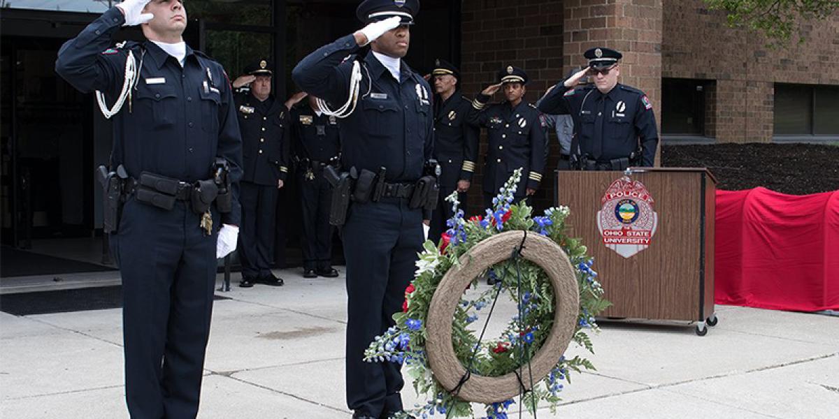 officers saluting at the memorial service in front of Blankenship Hall