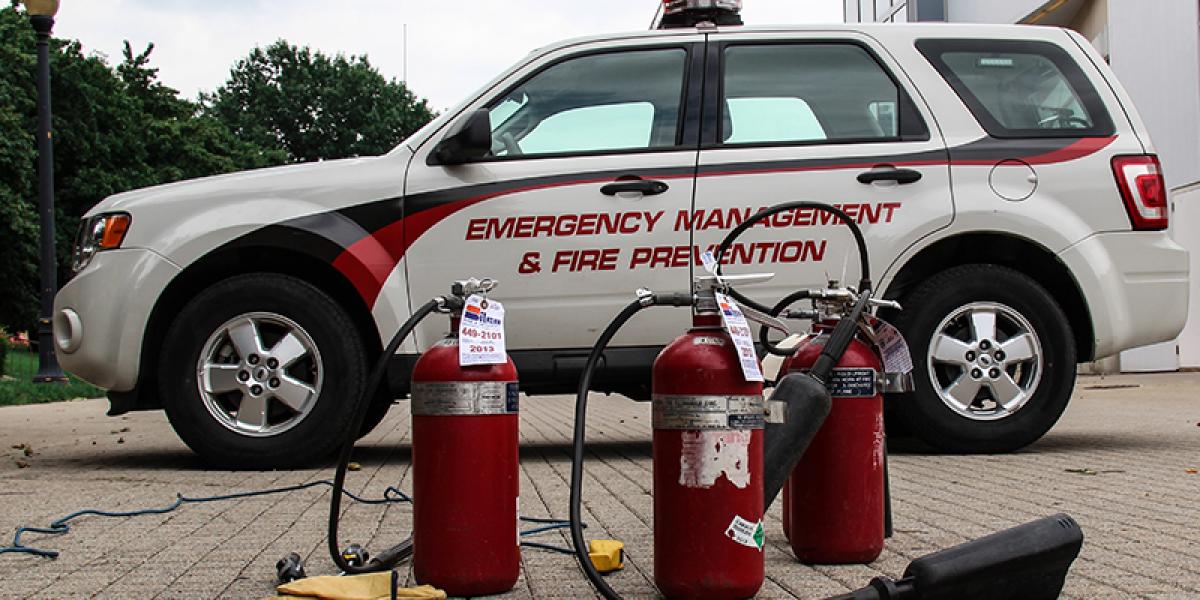 three fire extinguishers on pavers, in front of a emergency response vehicle