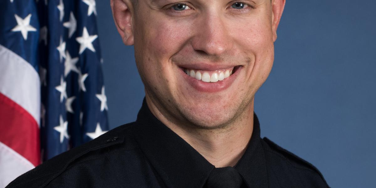 Officer Allan Horujko next to American flag