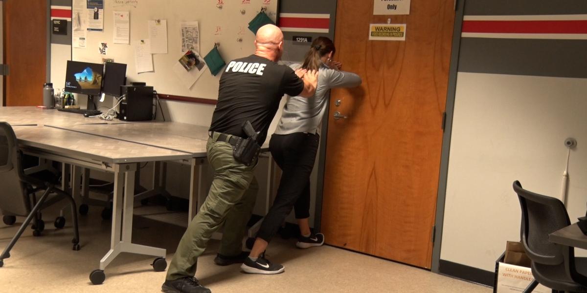 An OSUPD officer teaches a student how to hold a door shut in an emergency situation.