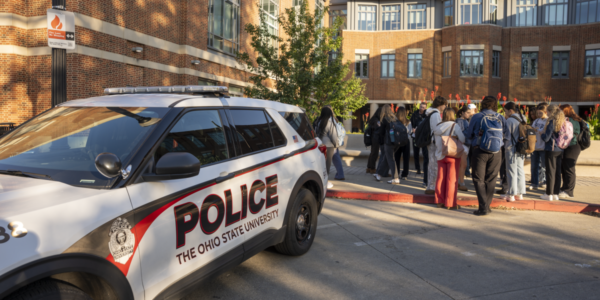 An OSUPD vehicle parked outside next to a group of students.