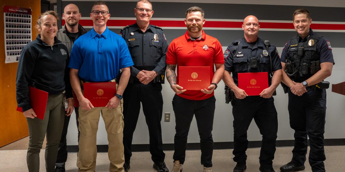 A group of officers stand, smiling holding an award.