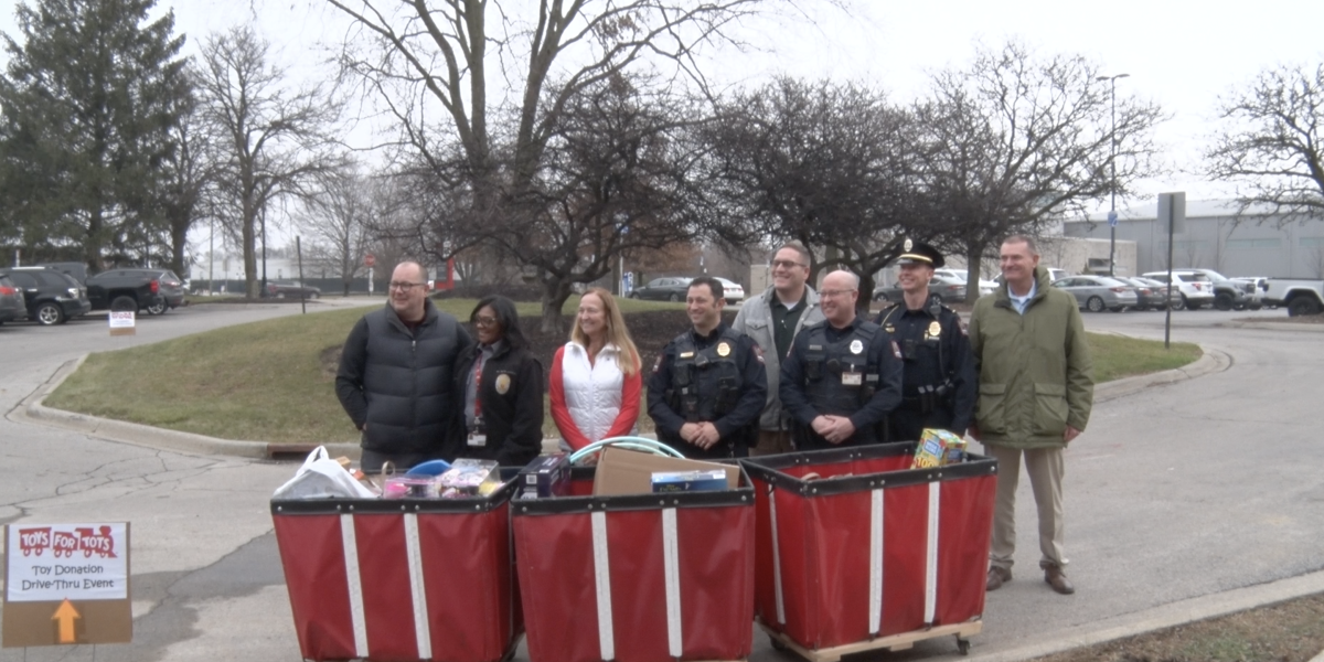Ohio State's Department of Public Safety smiles for a photo in front of bins full of toy donations.