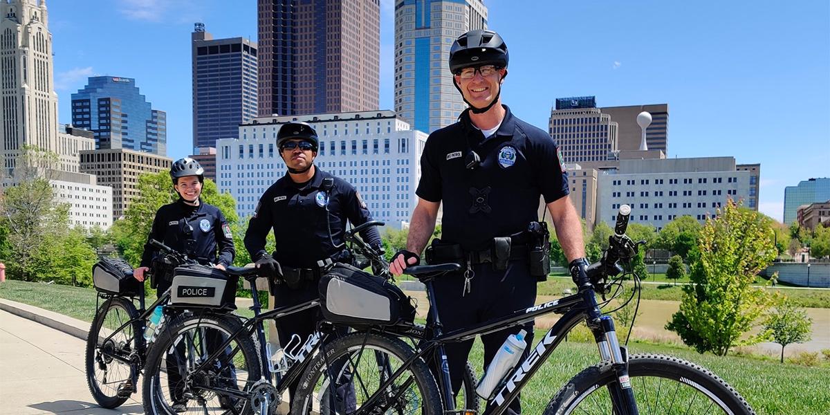 three OSUPD officers stand near their bikes