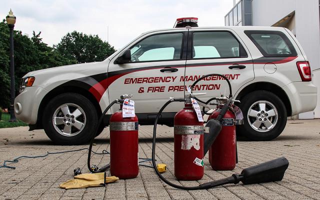 three fire extinguishers on pavers, in front of a emergency response vehicle