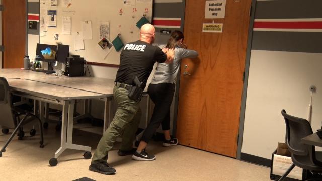 An OSUPD officer teaches a student how to hold a door shut in an emergency situation.