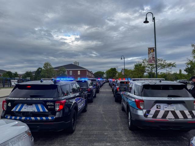 A line of first responder vehicles with their blue lights on.
