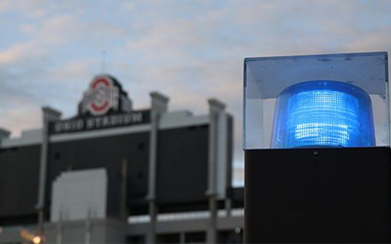 a light atop a police cruiser, with Ohio Stadium in the background