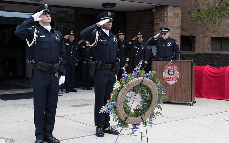 officers saluting at the memorial service in front of Blankenship Hall
