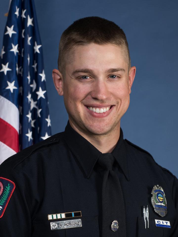 Officer Allan Horujko next to American flag