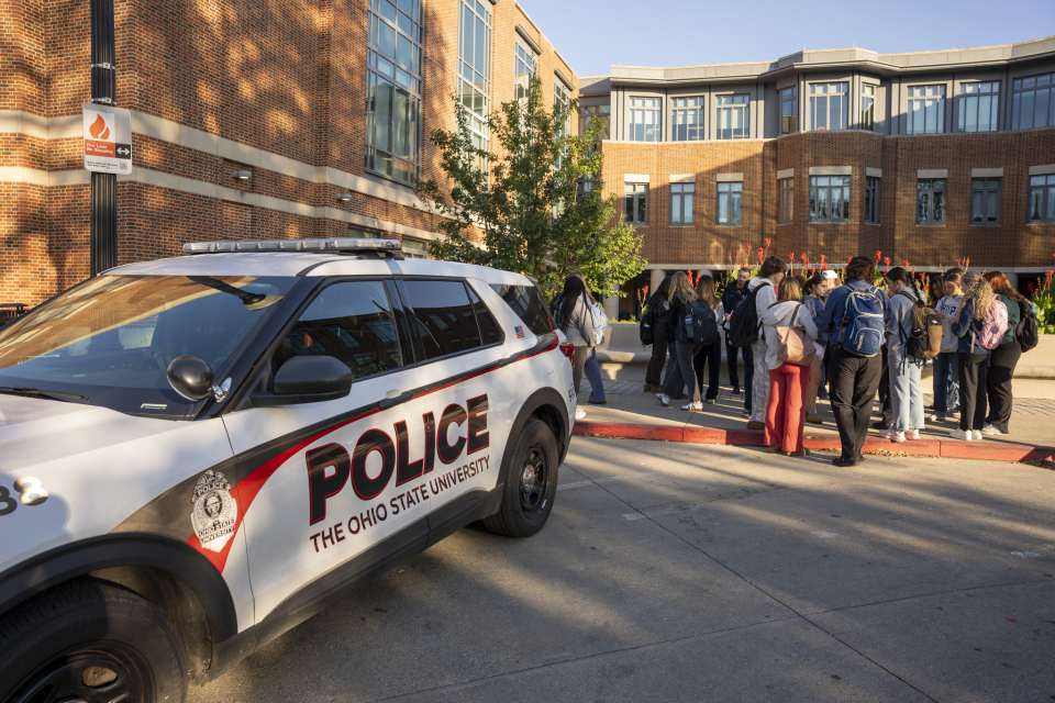 An OSUPD vehicle parked outside next to a group of students.