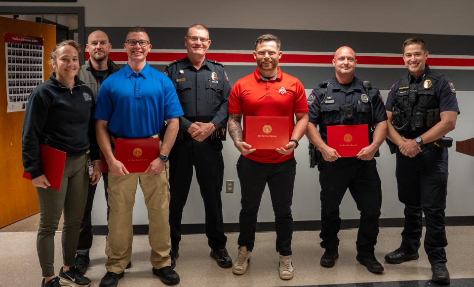 A group of officers stand, smiling holding an award.