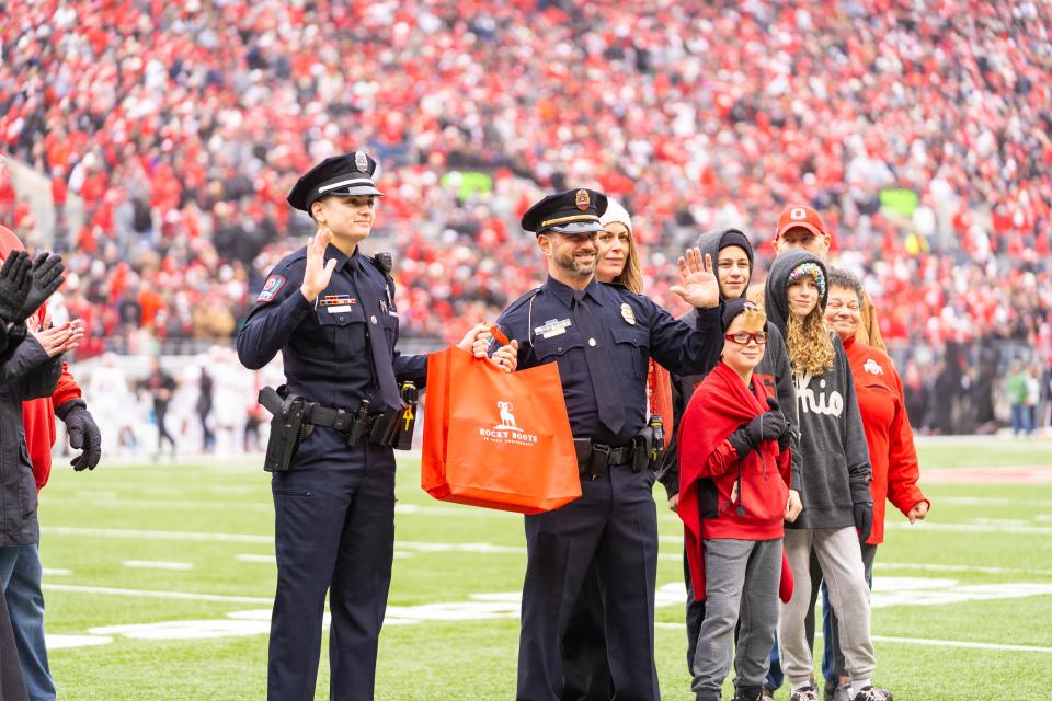 Lt. Shankle and Officer Ward waving at a crowd while smiling.
