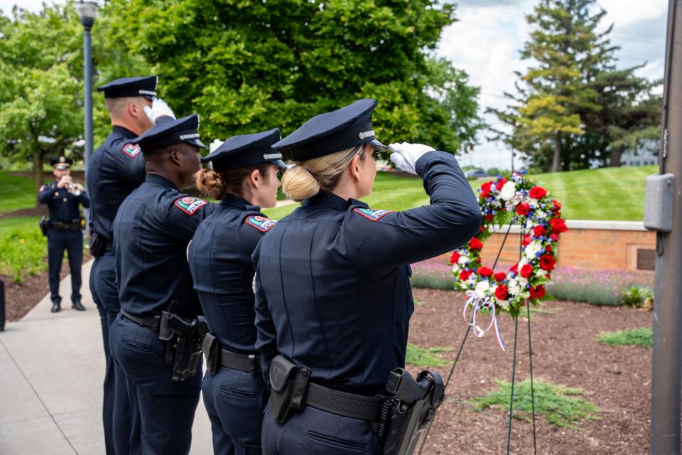 Four officers salute a flower wreath.