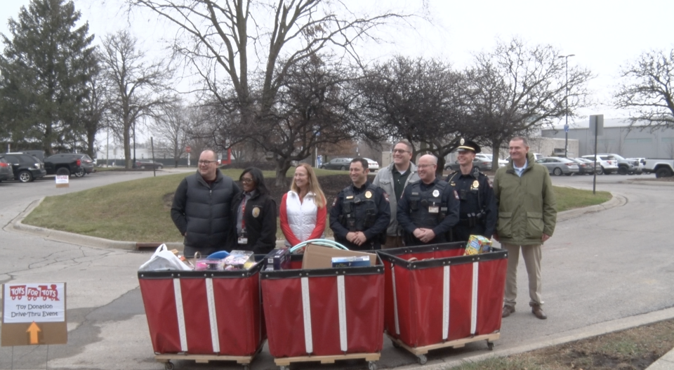 Ohio State's Department of Public Safety smiles for a photo in front of bins full of toy donations.