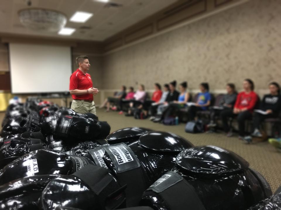 officer standing next to self-defense training gear, talking to students